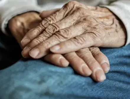 Carer holding the hands of a care home resident